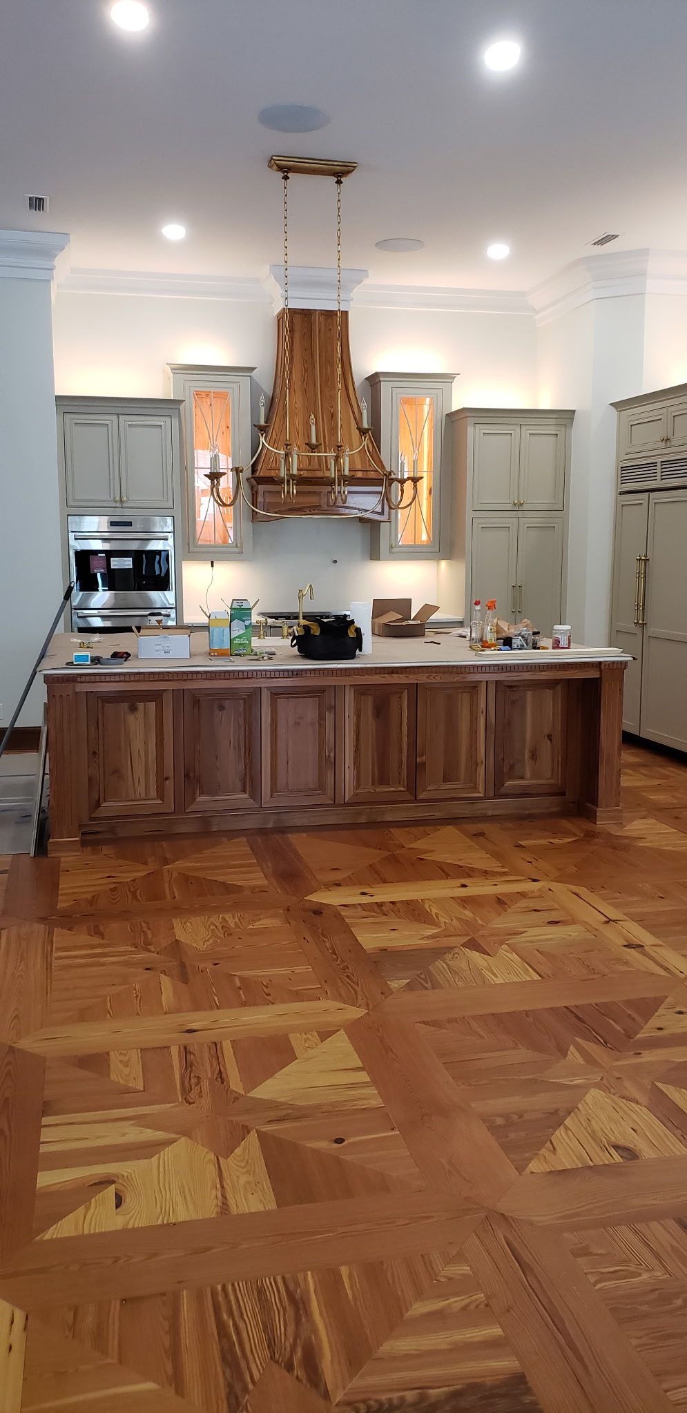 Kitchen island with brass chandelier and custom paneled cabinetry
