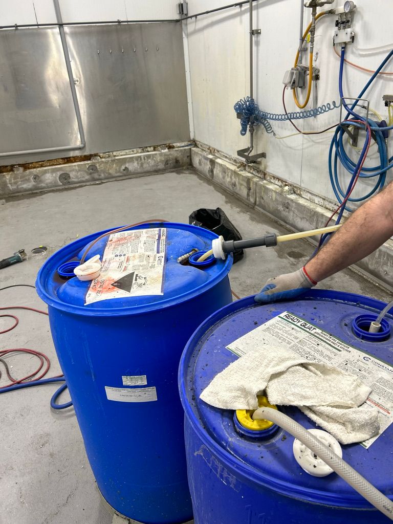 Two blue injection barrels with hose system set up for concrete crack injection repair in commercial facility