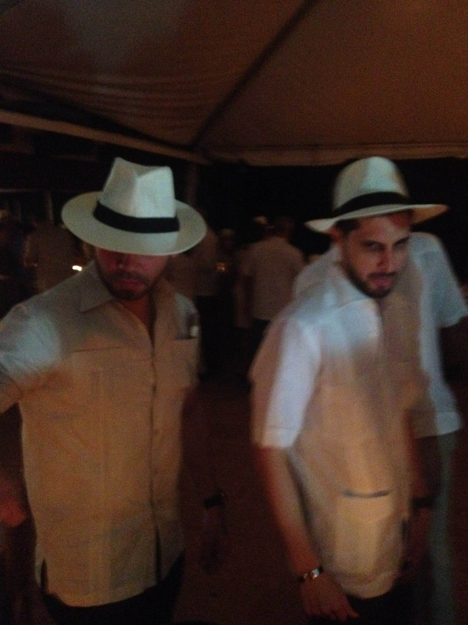 Two men in light-colored shirts and white Panama hats — 1950s Caribbean formal wear