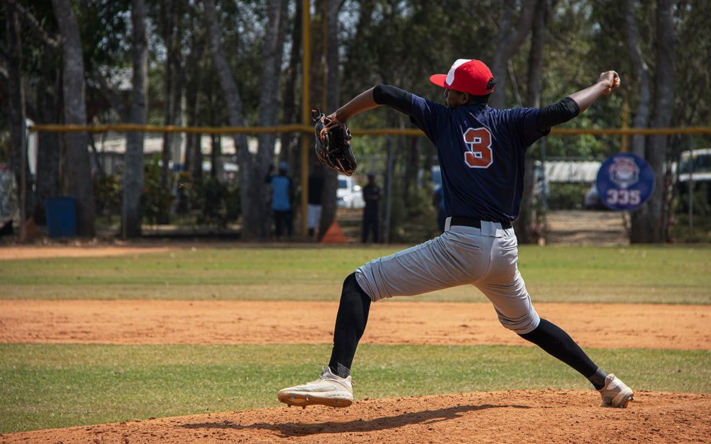 Dominican youth baseball player pitching on the mound during a game