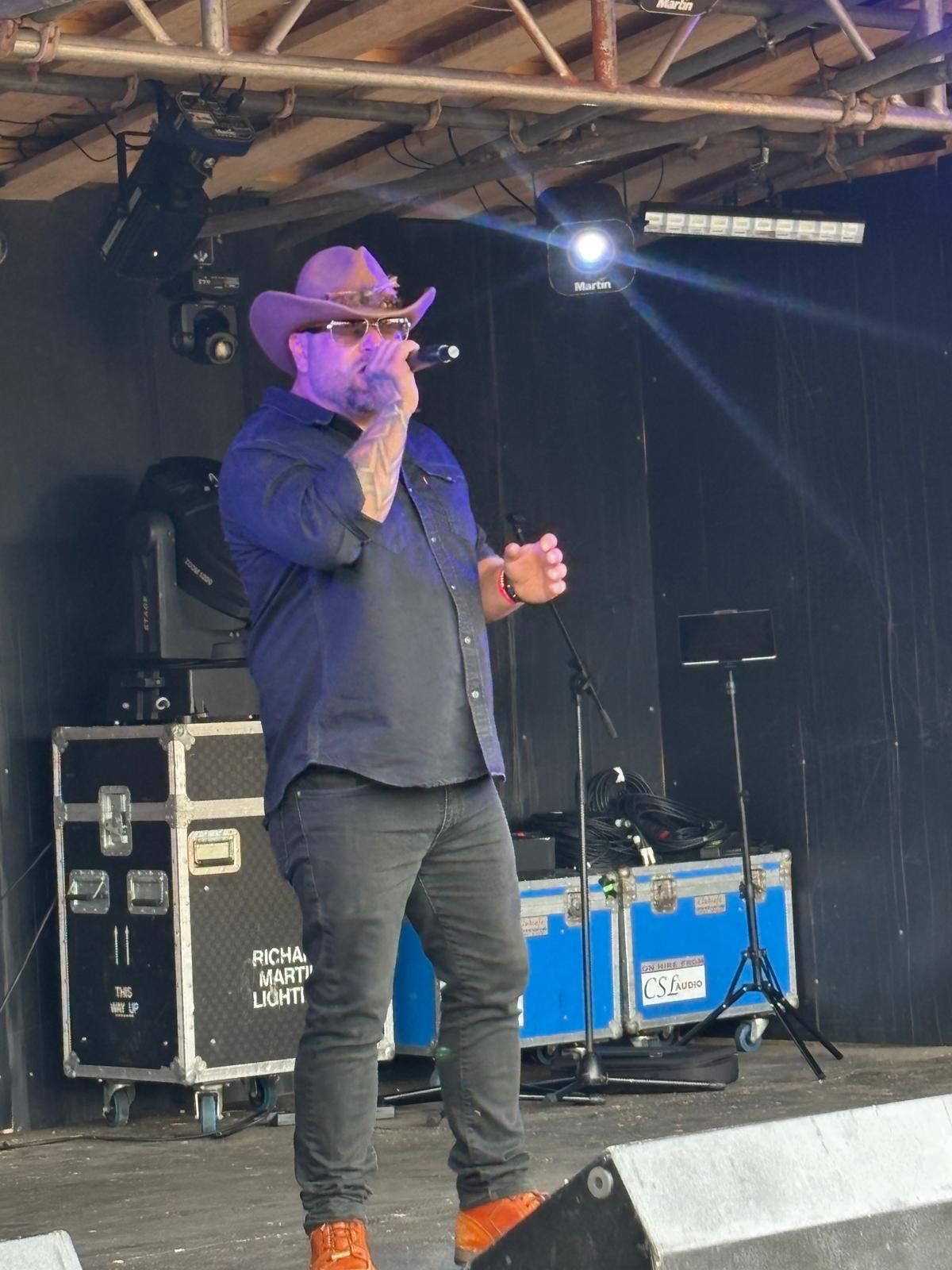 WAGGA live on stage with sunglasses and cowboy hat under stage lights