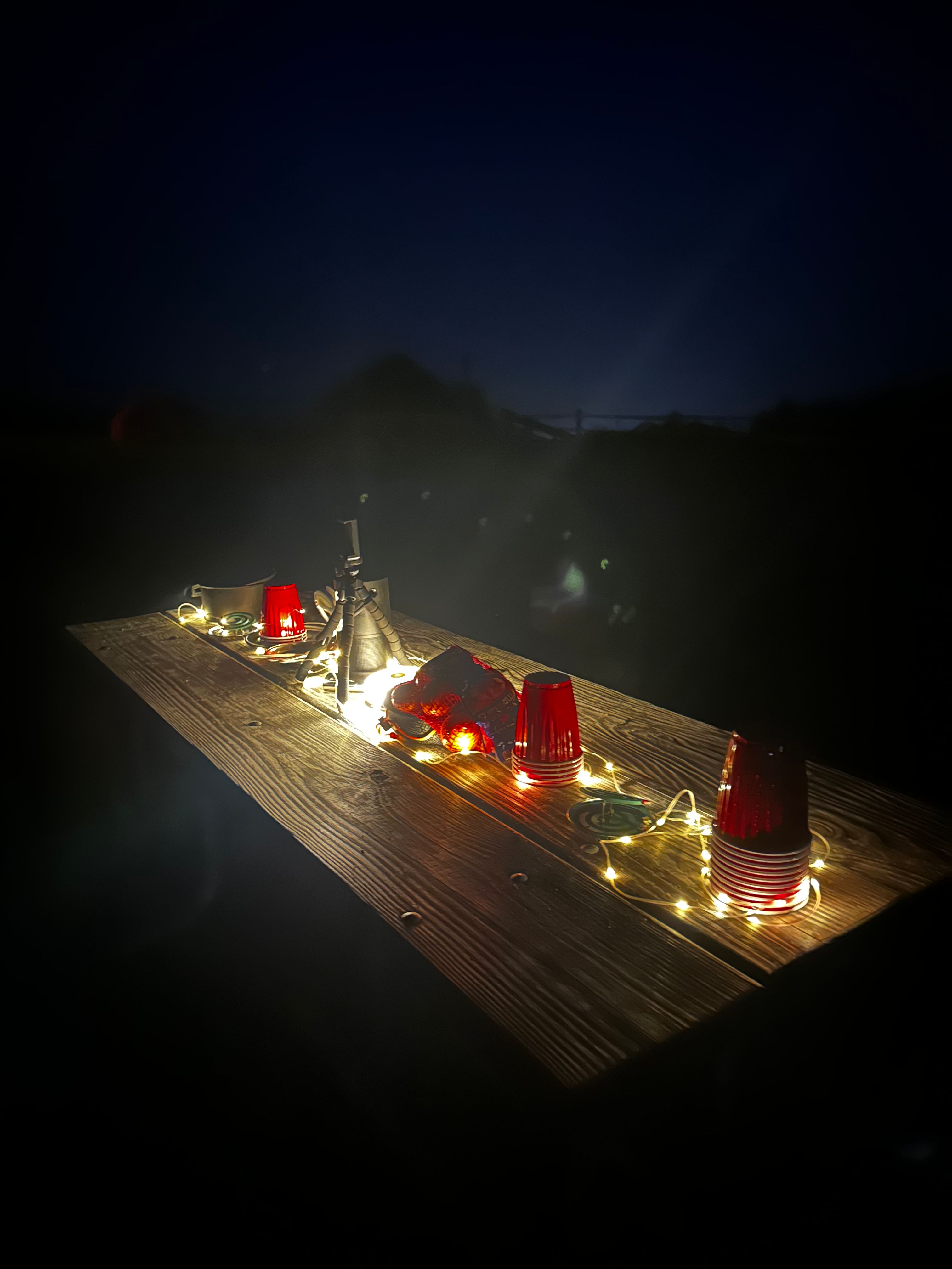 Night camping table with red plastic cups and string fairy lights — Hither Hills State Park, Montauk 2026